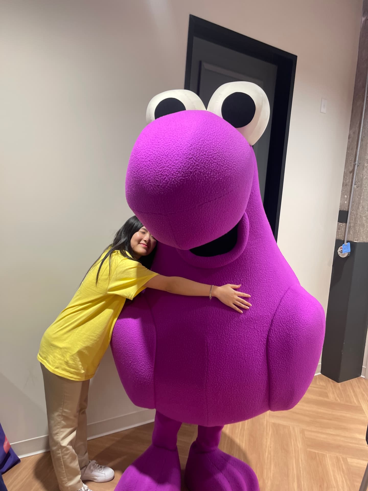 Josephine hugging a purple mascot at the office